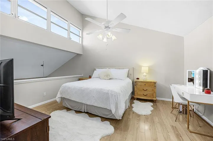 Bedroom with wood finished floors, a ceiling fan, and high vaulted ceiling