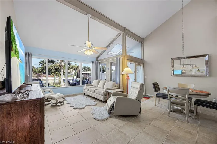 Living area featuring high vaulted ceiling, light tile patterned floors, a ceiling fan, and beamed ceiling