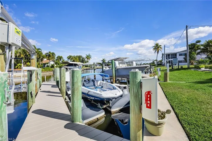 Dock with a water view, boat lift, and a lawn