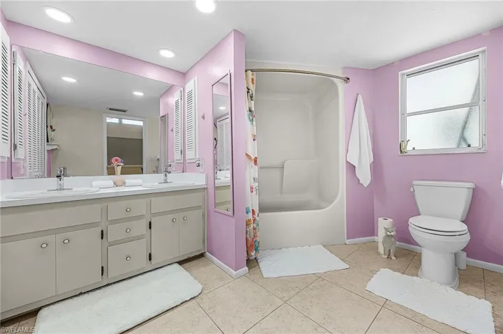 Bathroom with double vanity, light tile patterned floors, shower / bath combination with curtain, and recessed lighting