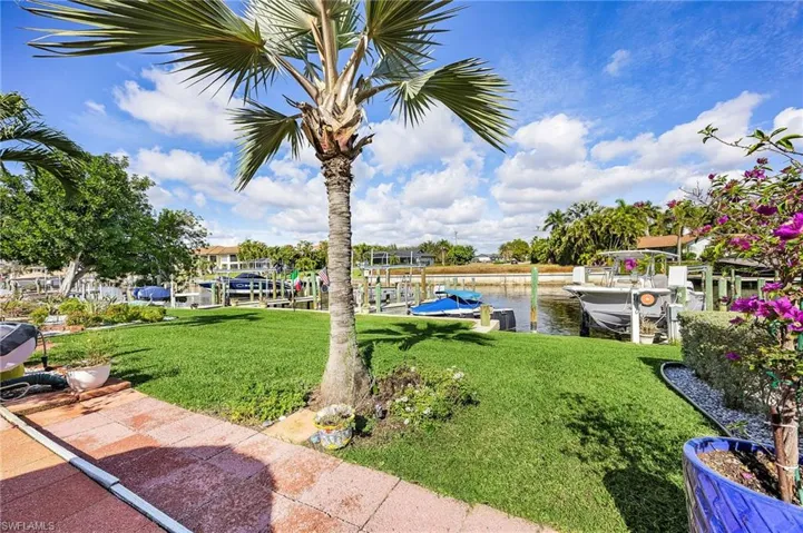 View of grassy yard with a water view, a dock, and boat lift