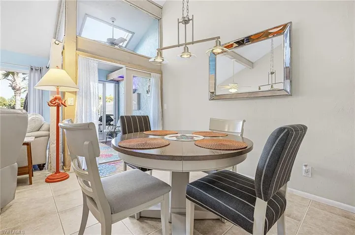 Dining area with high vaulted ceiling, ceiling fan, light tile patterned floors, and beamed ceiling