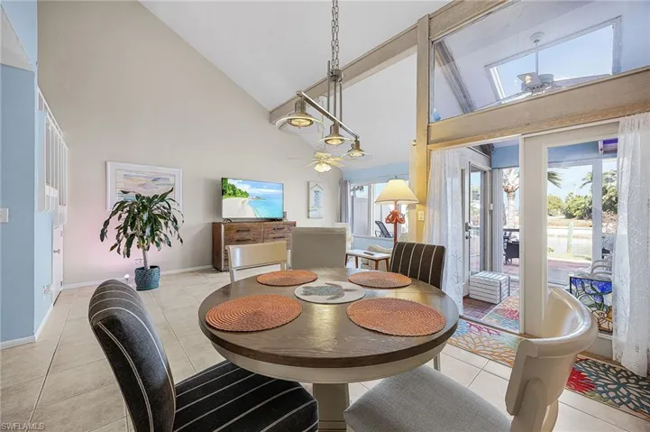 Dining space with high vaulted ceiling, ceiling fan, and light tile patterned flooring