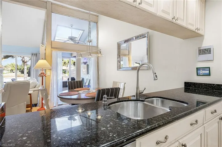 Kitchen with white cabinets, dark stone countertops, and open floor plan