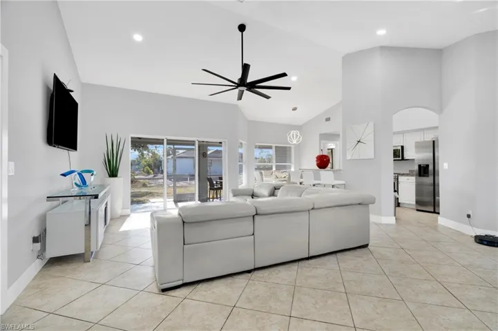 Living area with baseboards, ceiling fan, high vaulted ceiling, and light tile patterned floors