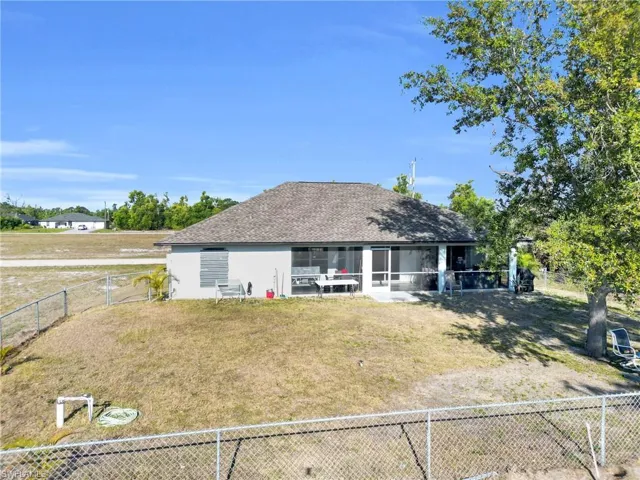 Rear view of property featuring a fenced backyard, a shingled roof, a sunroom, and a yard