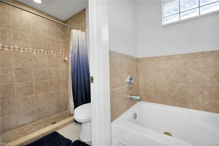 Bathroom featuring toilet, a tub to relax in, and a tile shower