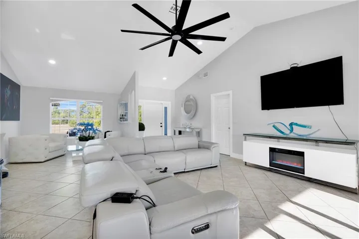 Living room featuring high vaulted ceiling, visible vents, a ceiling fan, and light tile patterned floors