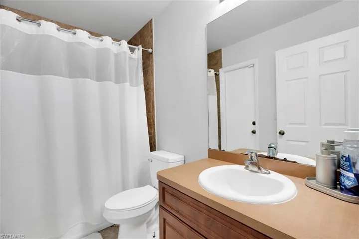 Bathroom featuring toilet, vanity, and curtained shower