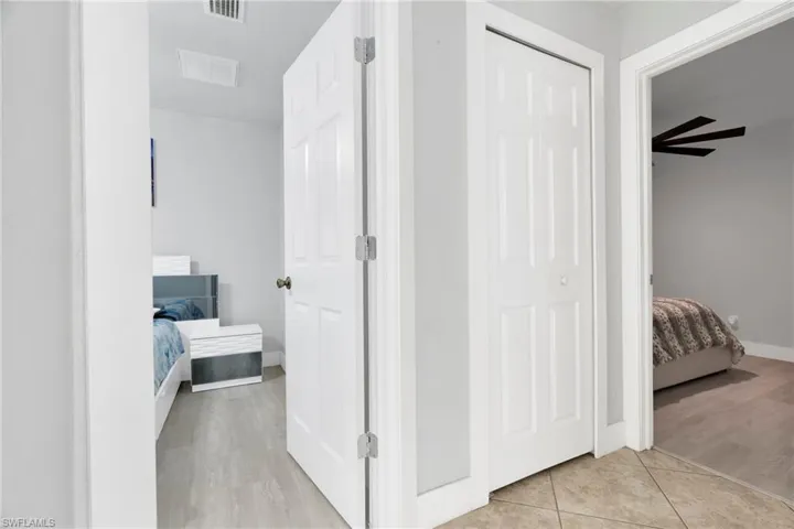Corridor featuring baseboards, visible vents, and light tile patterned floors