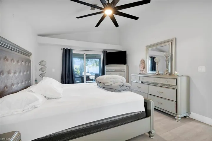 Bedroom featuring a ceiling fan, baseboards, light wood-style floors, and vaulted ceiling