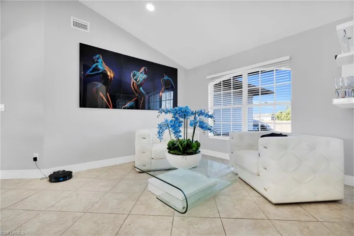 Living area with tile patterned floors, lofted ceiling, visible vents, and baseboards
