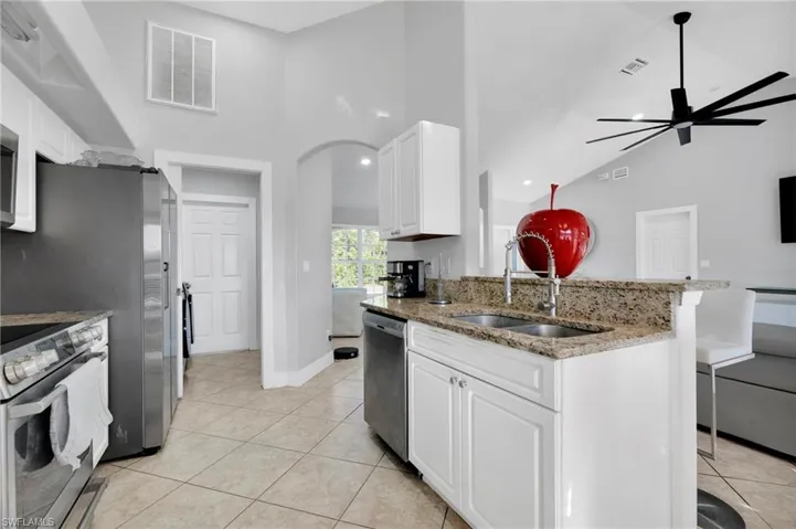 Kitchen featuring appliances with stainless steel finishes, visible vents, light tile patterned flooring, and a sink