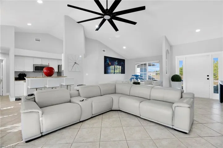 Living room with recessed lighting, light tile patterned floors, high vaulted ceiling, visible vents, and a ceiling fan