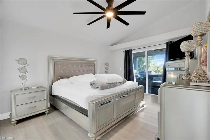 Bedroom with a ceiling fan, light wood-style floors, access to exterior, and vaulted ceiling