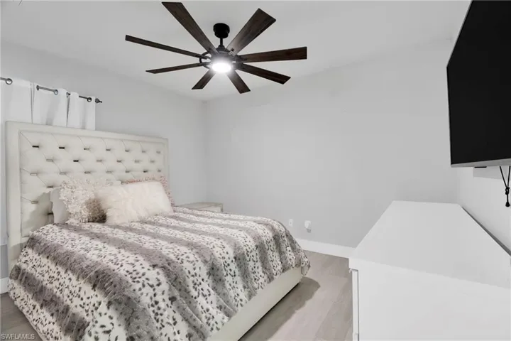 Bedroom with light wood-style flooring, baseboards, and ceiling fan