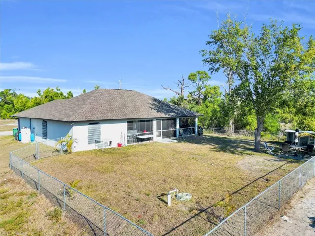View of front of property featuring a front yard, stucco siding, a fenced backyard, a shingled roof, and a sunroom