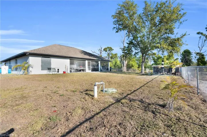Back of property featuring stucco siding, a fenced backyard, and a lawn