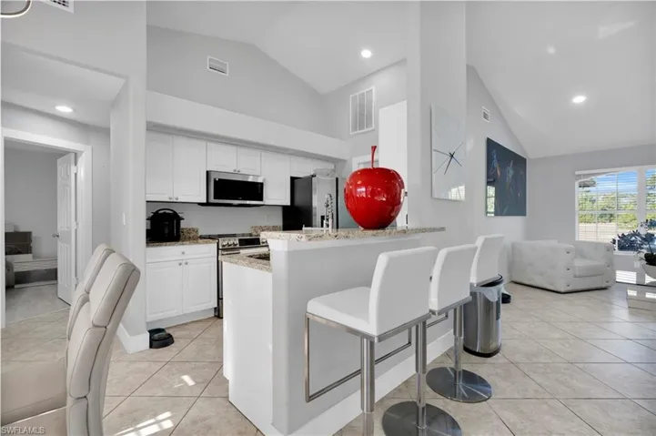 Kitchen featuring stainless steel appliances, light tile patterned flooring, visible vents, white cabinets, and a peninsula