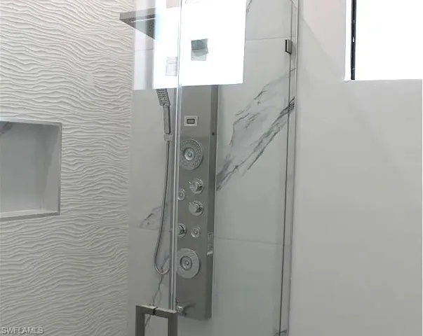 Contemporary shower enclosure featuring a multi-function shower panel with integrated handheld sprayer, clear glass door, and polished chrome hardware