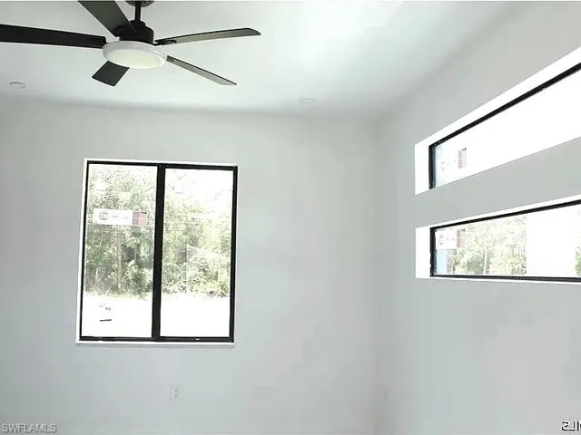 Room featuring a contemporary ceiling fan with integrated lighting, a large rectangular window, and two horizontal transom windows