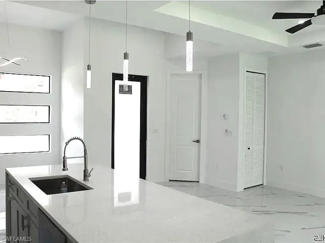 Spacious kitchen island featuring a light-toned countertop, integrated sink, and modern pull-down faucet