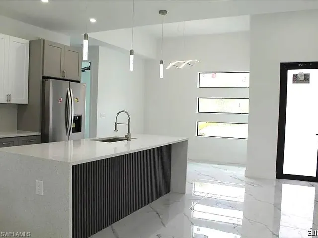 Kitchen island featuring a waterfall countertop and fluted paneling