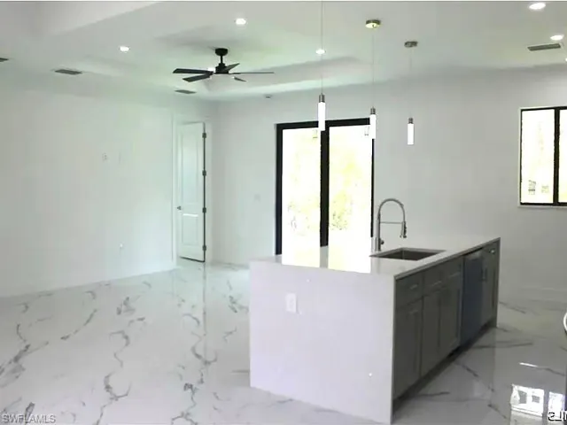 Open-concept living space featuring a kitchen island with integrated sink, pendant lighting, contemporary ceiling fan, recessed lighting, and large format marble-look flooring