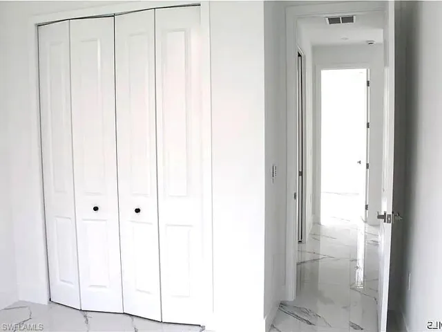 White bi-fold closet doors with black hardware, complementing the polished stone-look flooring