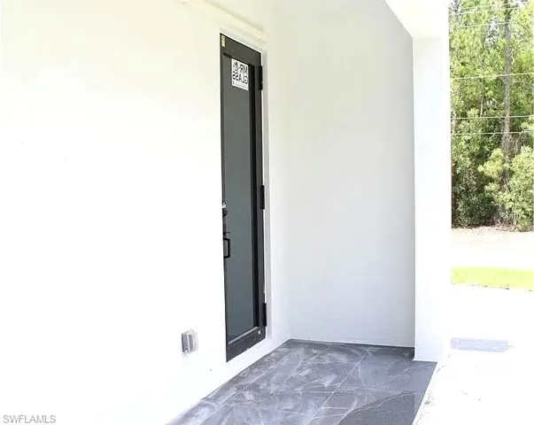 Black-framed glass entry door with a privacy film, set within a white stucco exterior