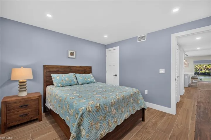 Recessed ceiling lighting, wood-finish flooring, white solid core doors, and a wood-finish bed frame