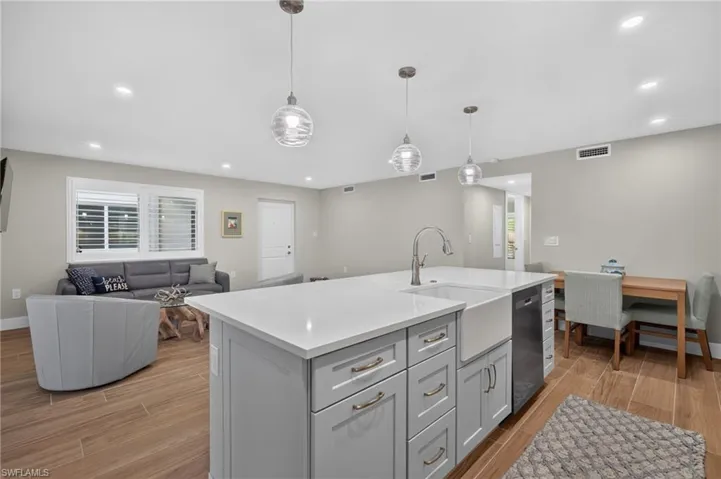 Kitchen island with white countertop, integrated farmhouse sink, and stainless-steel appliances