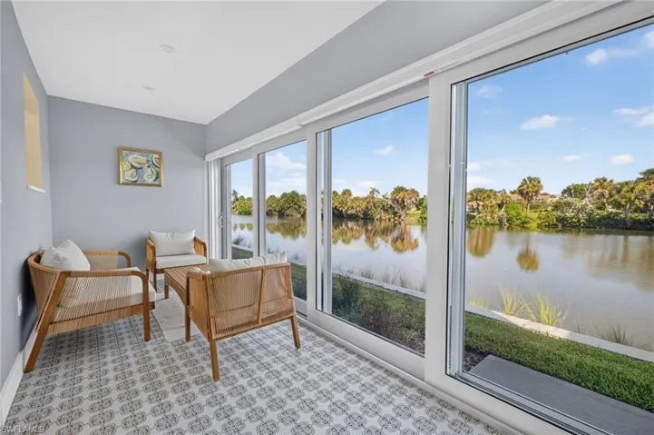 Expansive sliding glass doors, patterned floor tile, recessed ceiling lighting, and a serene water backdrop