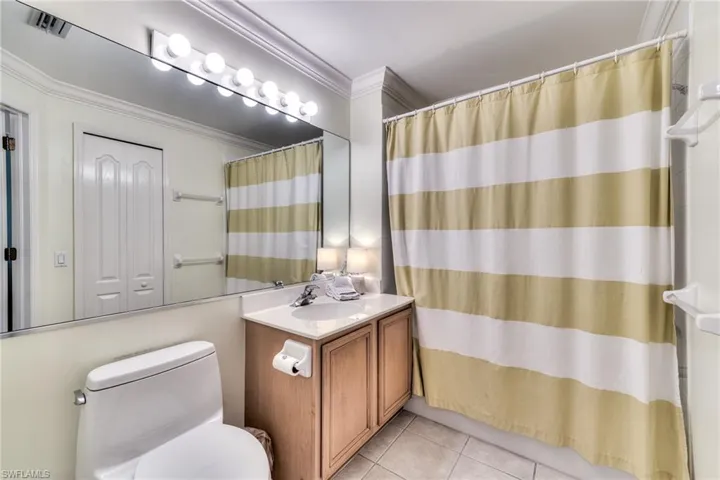 Bathroom featuring walk in shower, ornamental molding, vanity, tile patterned flooring, and toilet