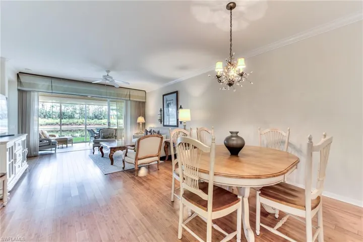 Dining space with ceiling fan with notable chandelier, light wood-type flooring, and crown molding
