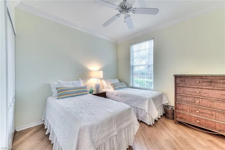 Bedroom with a closet, ceiling fan, crown molding, and light wood-type flooring
