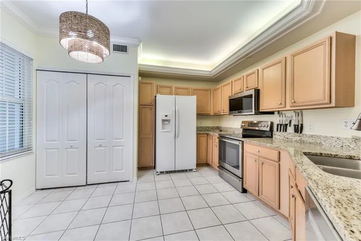 Kitchen featuring ornamental molding, hanging light fixtures, a notable chandelier, and appliances with stainless steel finishes