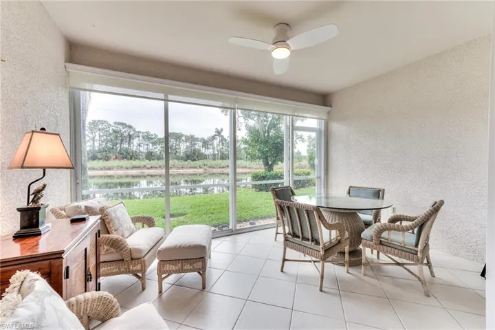 Sunroom / solarium featuring ceiling fan and a water view