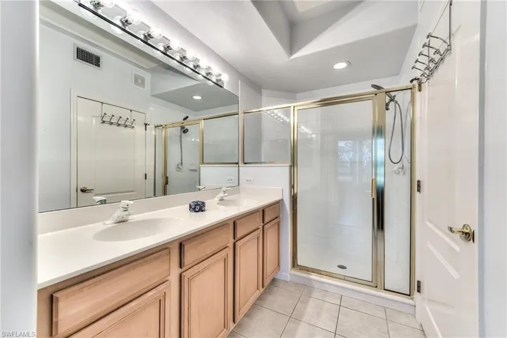 Bathroom featuring tile patterned floors, vanity, and walk in shower