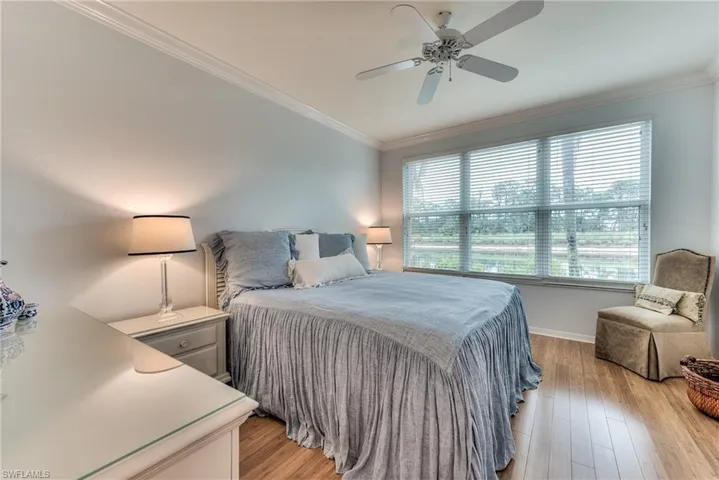 Bedroom with multiple windows, light hardwood / wood-style floors, ceiling fan, and ornamental molding