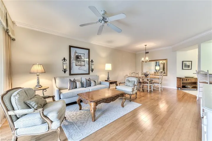 Living room featuring crown molding, light hardwood / wood-style flooring, and ceiling fan with notable chandelier