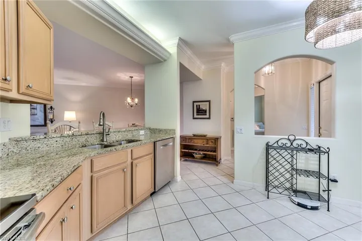 Kitchen featuring sink, light tile patterned floors, dishwasher, a chandelier, and hanging light fixtures