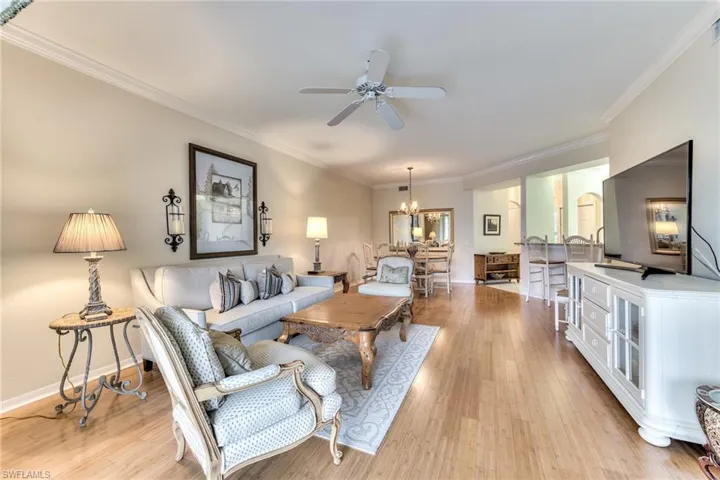 Living room featuring crown molding, light hardwood / wood-style flooring, and ceiling fan with notable chandelier