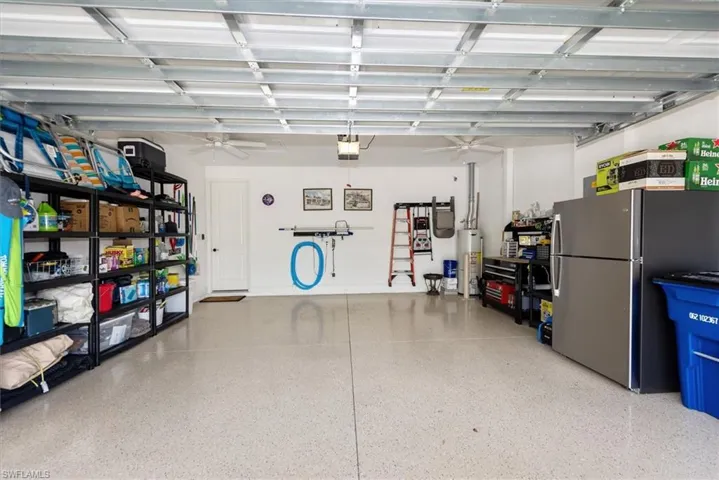 Garage featuring freestanding refrigerator, ceiling fan, gas water heater, and a garage door opener