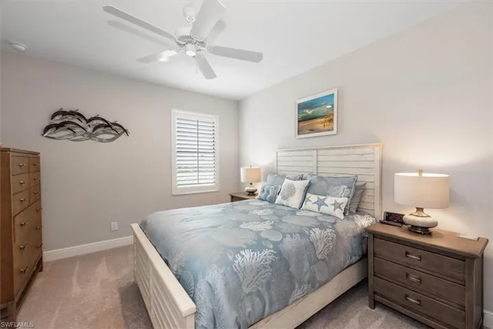 Bedroom with light colored carpet, baseboards, and ceiling fan