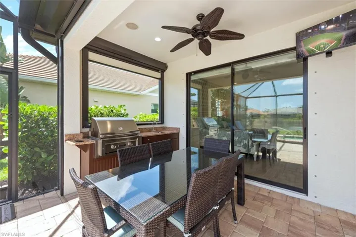Sunroom / solarium Outdoor kitchen, TV, a ceiling fan, outdoor dining area, and a sink