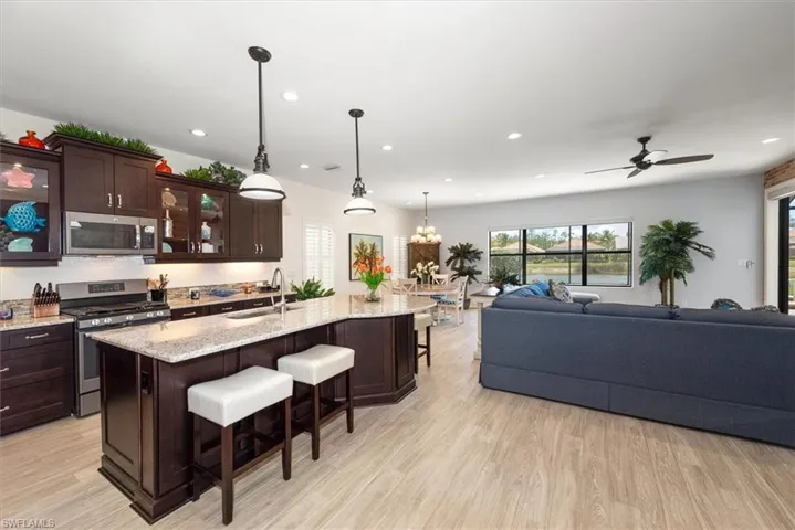 Kitchen featuring appliances with stainless steel finishes, a sink, a kitchen bar, open floor plan, and dark brown cabinets
