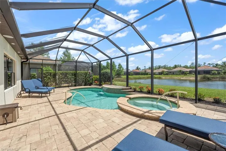 View of pool featuring a water view, a patio area, a pool with connected hot tub, and a lanai