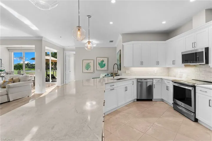 Kitchen with open floor plan, stainless steel appliances, white cabinetry, light stone countertops, and tasteful backsplash