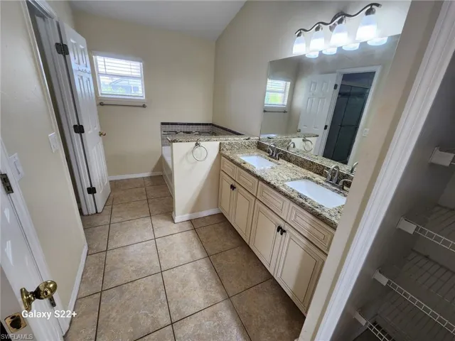 Bathroom with tile patterned flooring, vanity, and a washtub